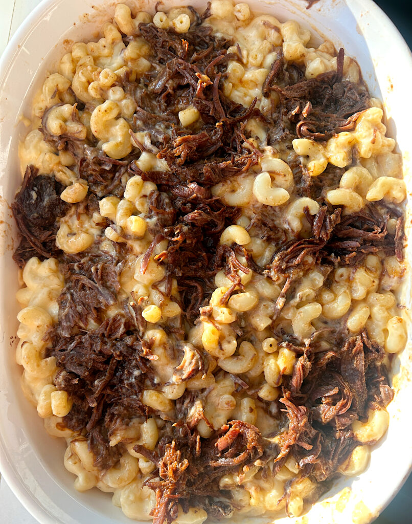 a casserole dish of cheesy pasta with bbq venison meat on top