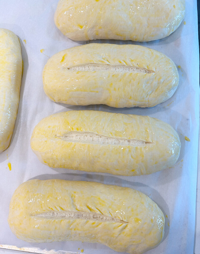 a baking sheet of unbaked hoagie rolls