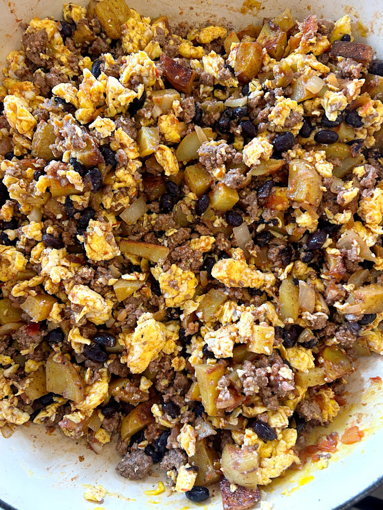 a skillet of scrambled eggs, potato, black beans and ground meat