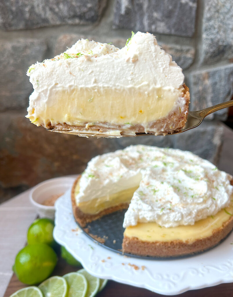 a white platter with a key lime pie on top topped with whipped cream
