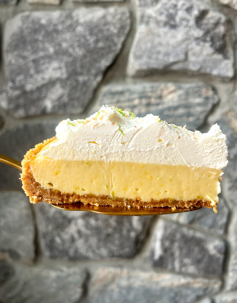 a slice of pie with graham crust, key lime filling and whipped cream
