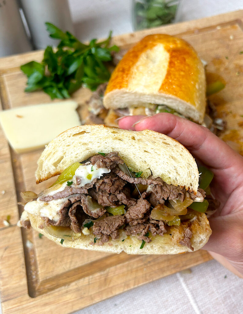 half of a sandwich with venison steak, mozzarella cheese and green peppers