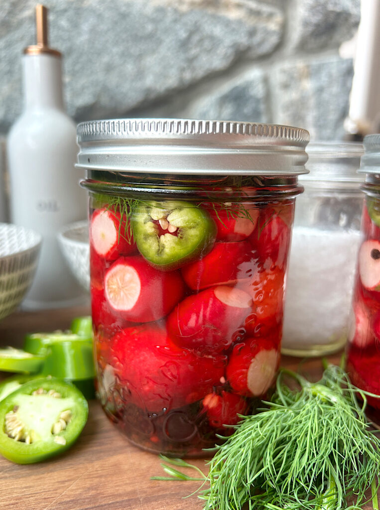 a jar full of pickled radishes with jalapeños and fresh dill