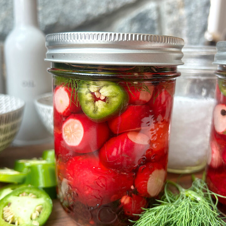 a jar full of pickled radishes with jalapeños and fresh dill