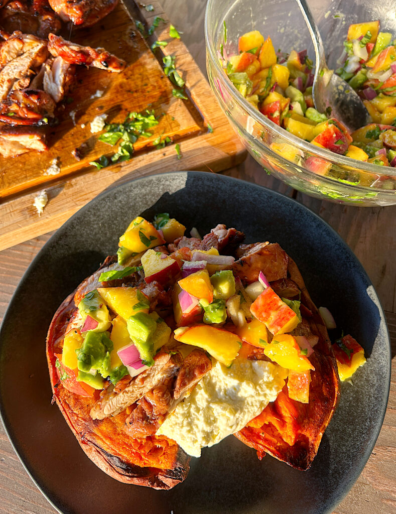 a baked sweet potato with feta, peach and avocado salsa and grilled chicken on top