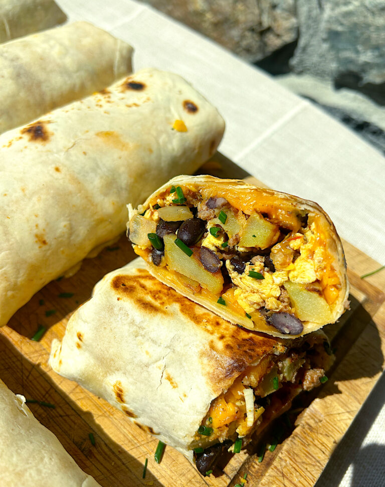 a wood board topped with homemade breakfast burritos