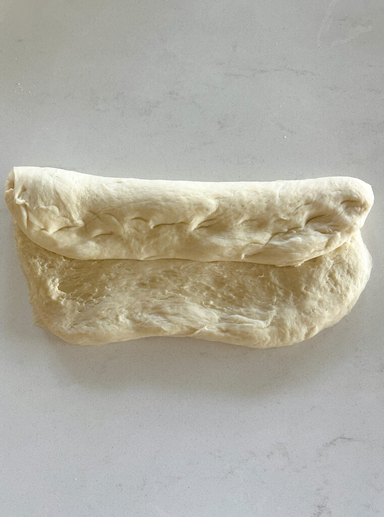 a log of bun dough on a white counter