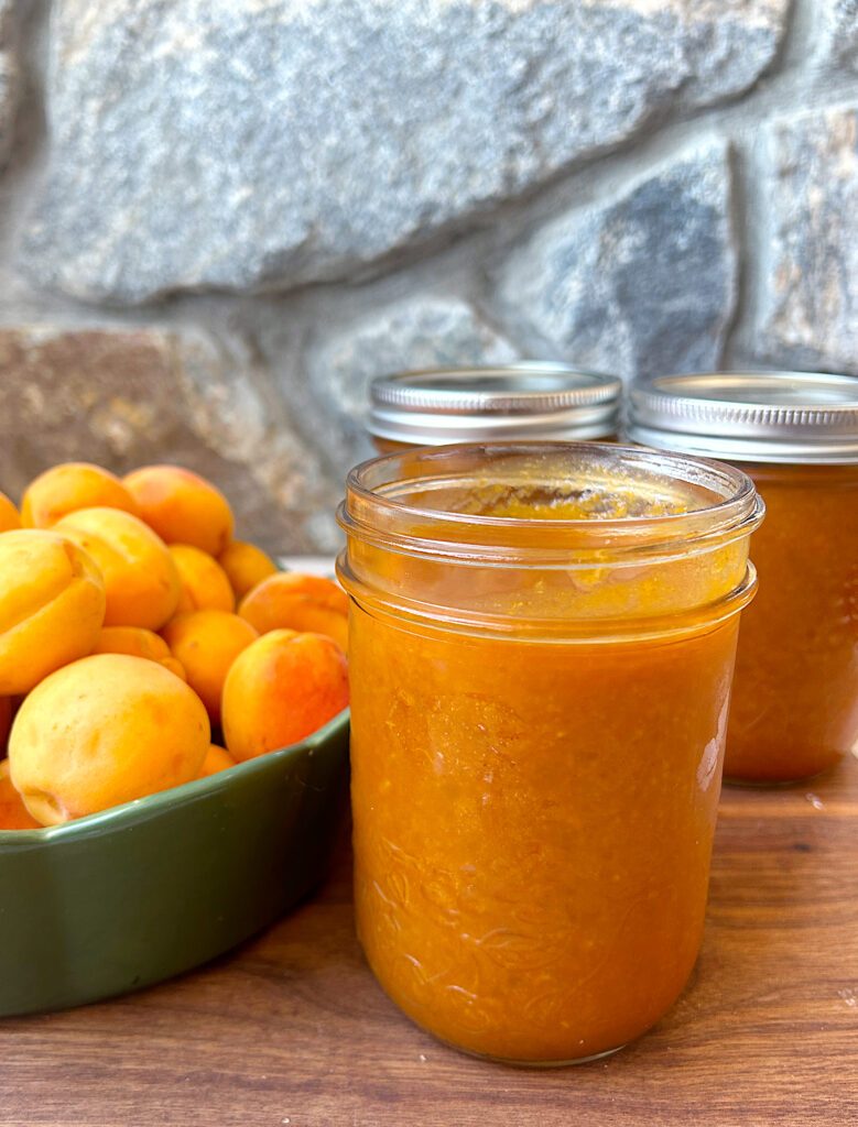a jar of homemade apricot bbq sauce on a wood board