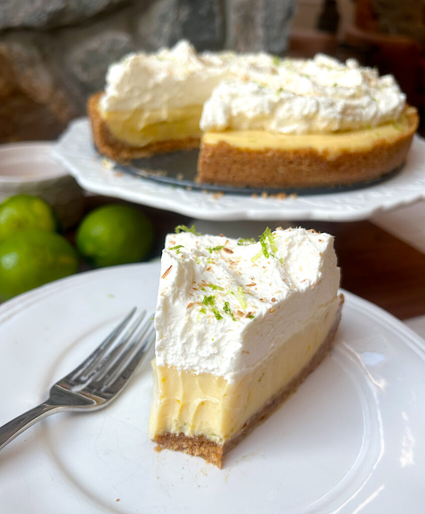 a slice of key lime pie topped with whipped cream on a white plate