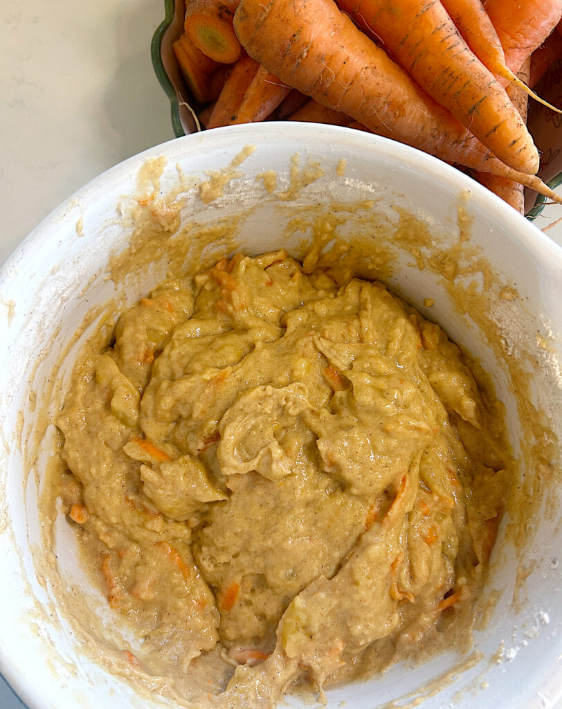 a white bowl of carrot muffin batter