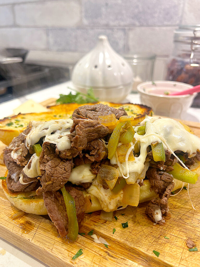 a hoagie roll topped with venison steak strips, peppers and mozzarella cheese