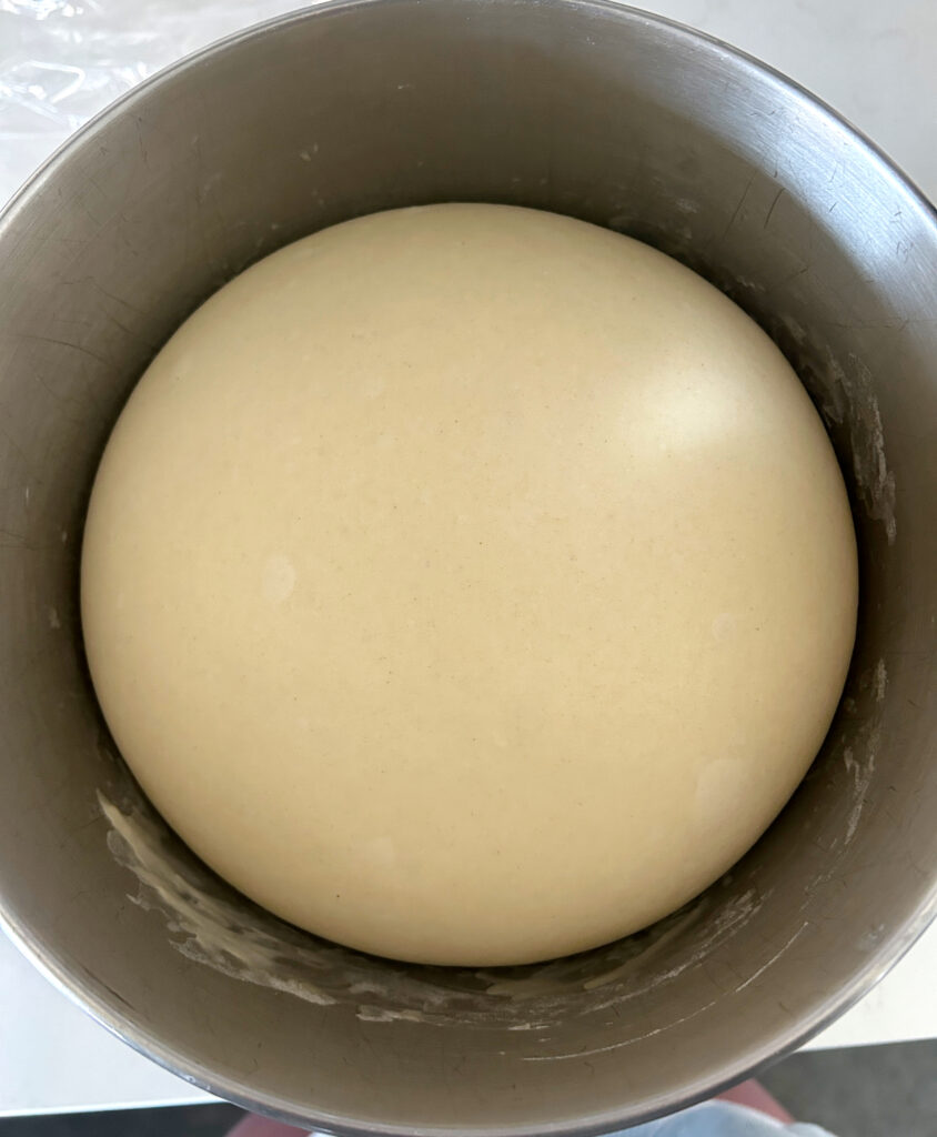 a stainless bowl of risen bun dough