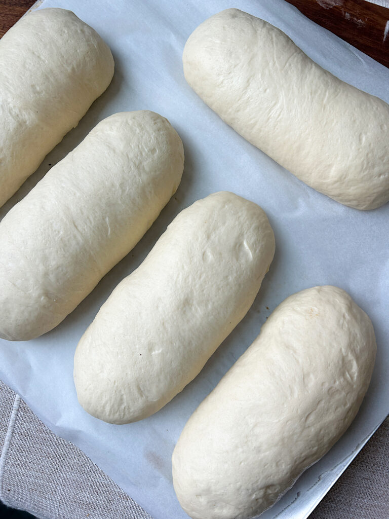 a baking sheet of unbaked hoagie rolls