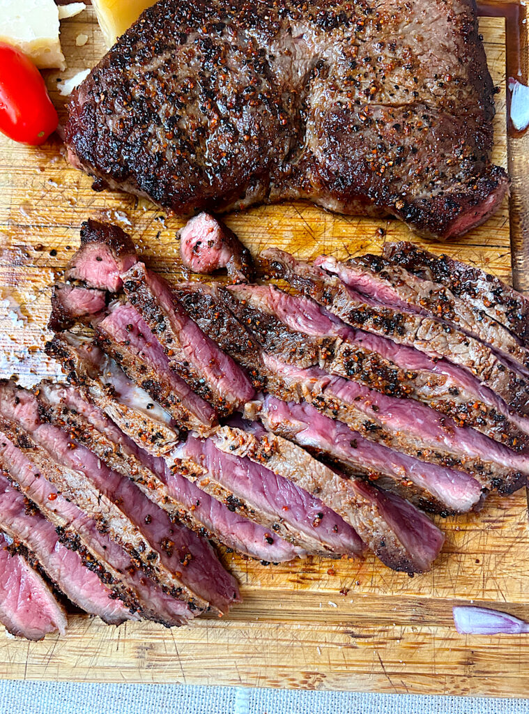 a wood board with sliced steak