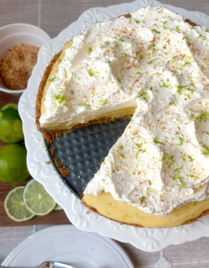 a cake stand with a lime pie topped with a thick layer or whipped cream