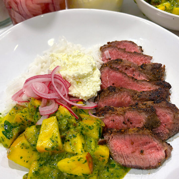 a white bowl with rice, sliced steak, chiichurri, peaches and pickled onions