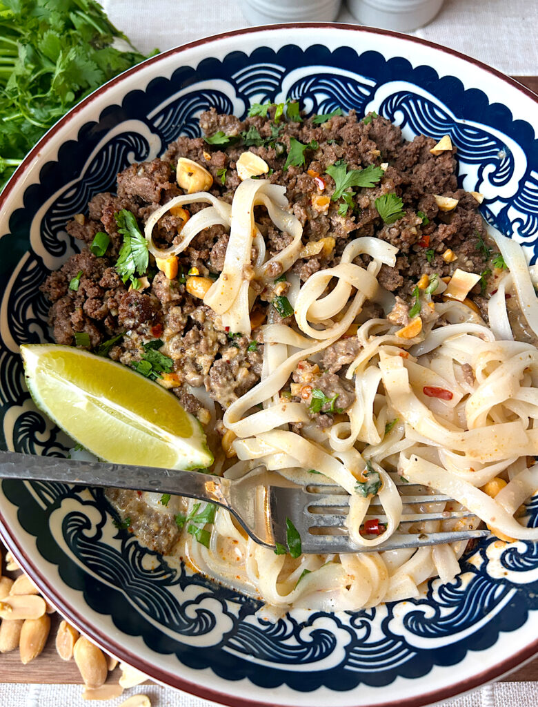 a blue and white bowl with noodles, broth and ground venison