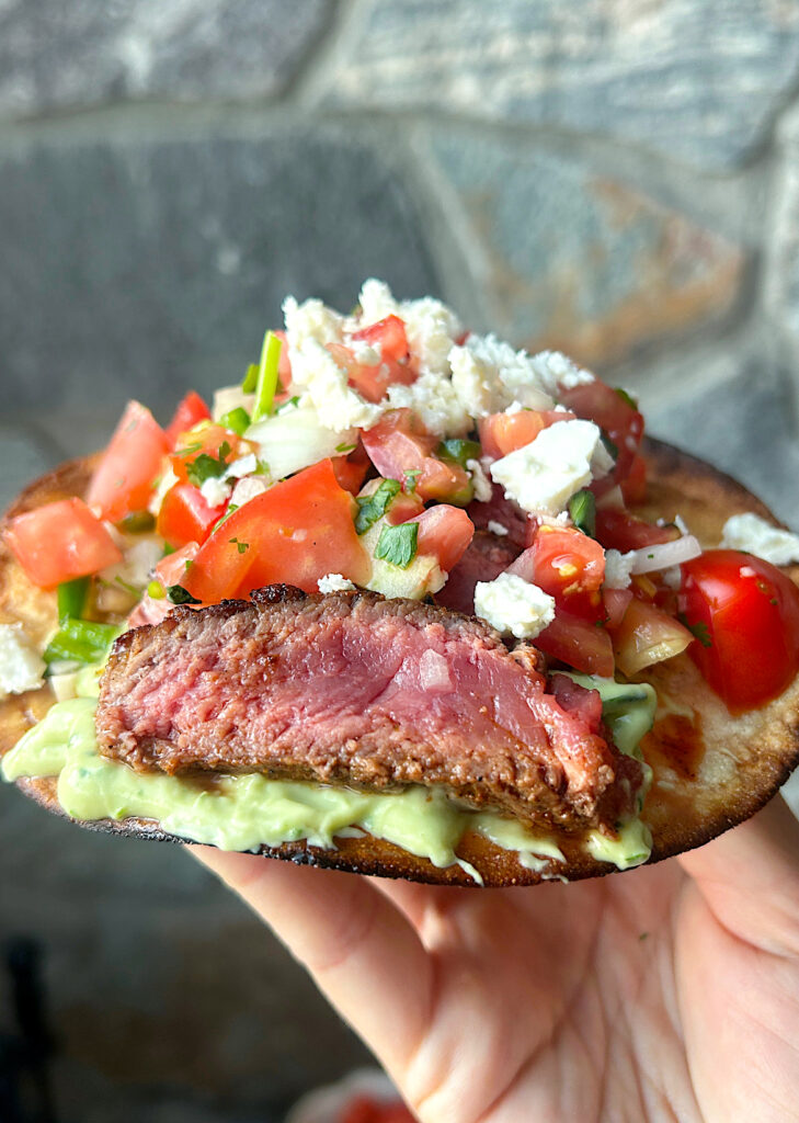 a crispy steak tostada with avocado sauce and pice de Gallo