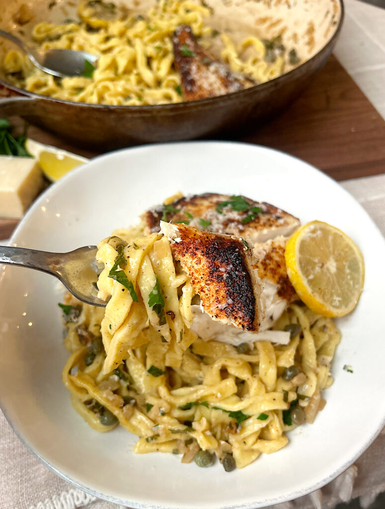 a bowls of linguini in a lemon and caper whit wine sauce with crispy white fish