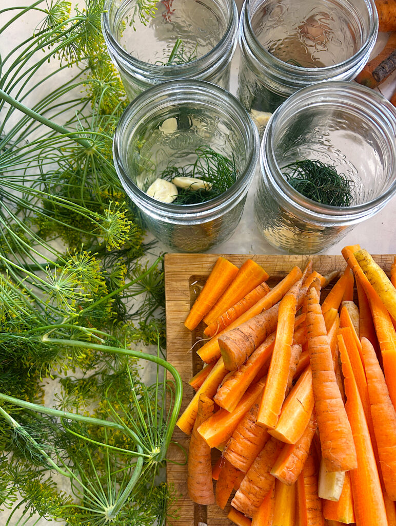 sliced carrot stick on a wood board, with fresh dill beside