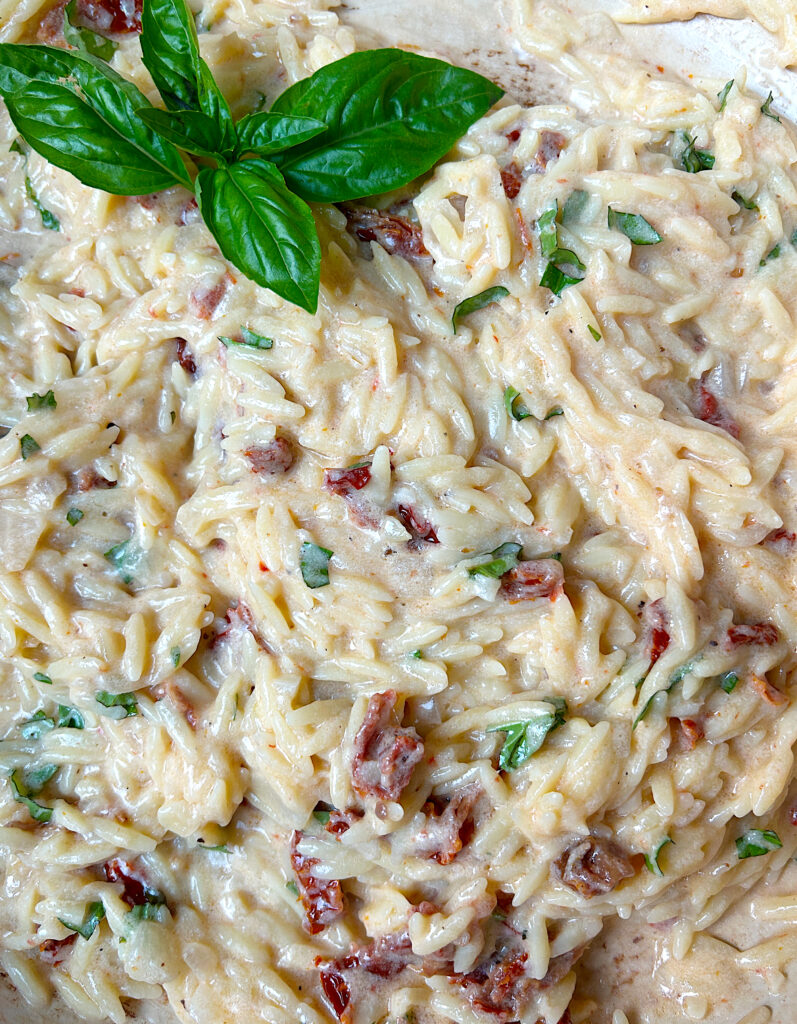 a skillet full of creamy orzo with basil and tomatoes