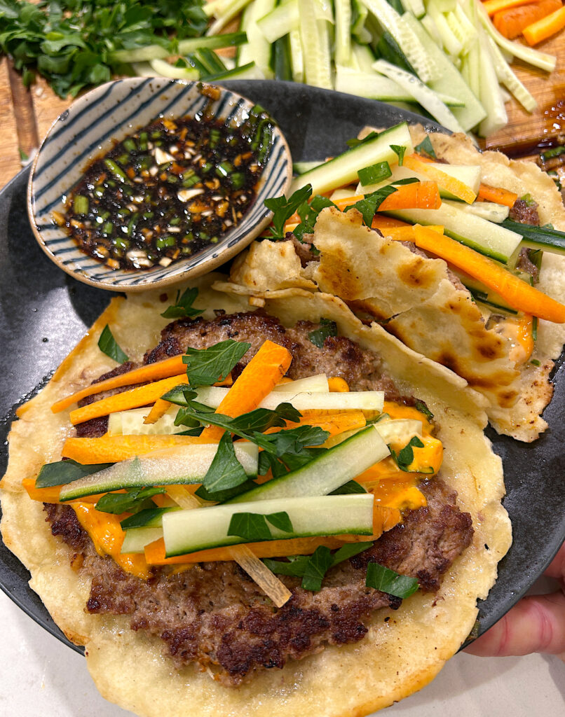 a plate of smash tacos with spicy mayo, cucumber, carrots and a side of soy dipping sauce