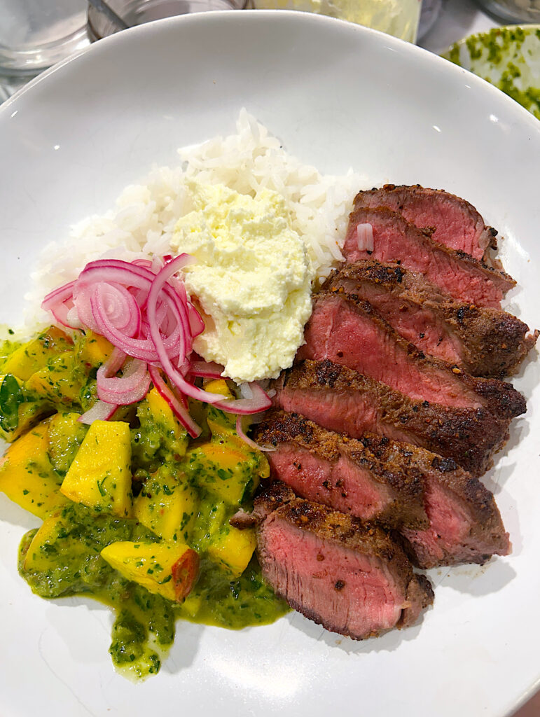 a rice bowl with steak, whipped feta, peaches and chimichurri sauce