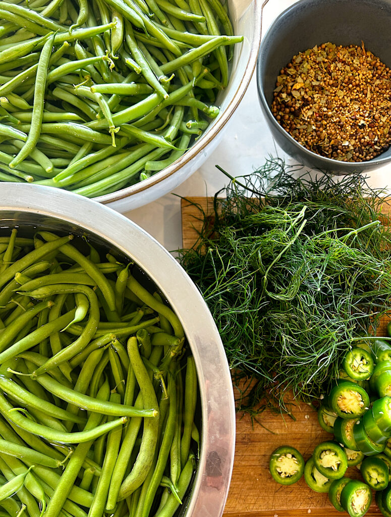 bowls of green beans with fresh dill and jalapeños on the side