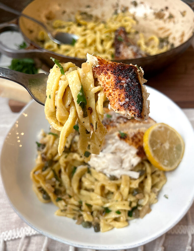 a fork full of lemon pasta with a bite of halibut