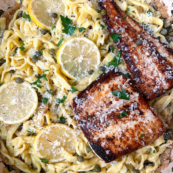 a skillet of lemon caper pasta with crispy halibut on top