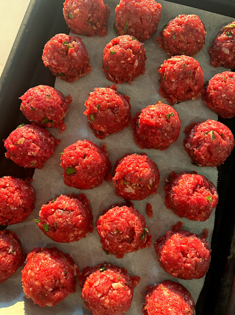 a tray of uncooked meatballs