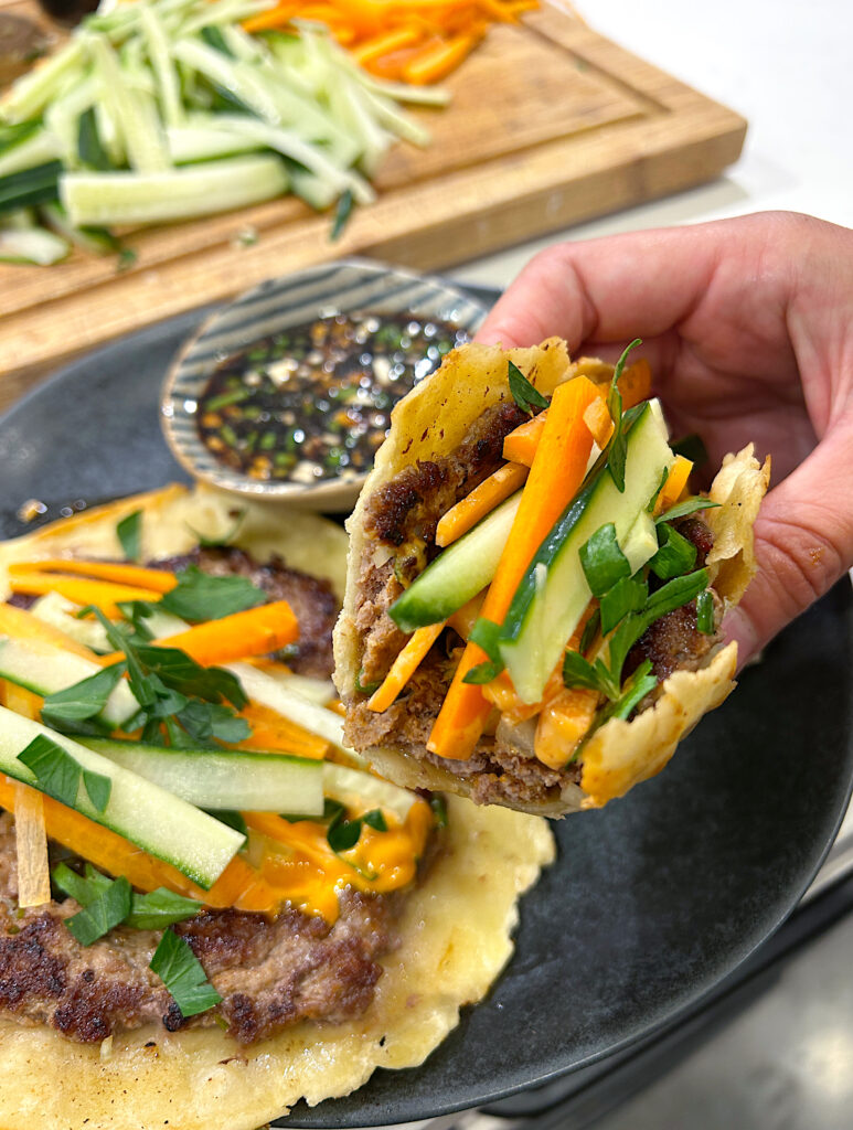 an asian inspired taco with ground meat, cucumbers, carrots and a soy dipping sauce