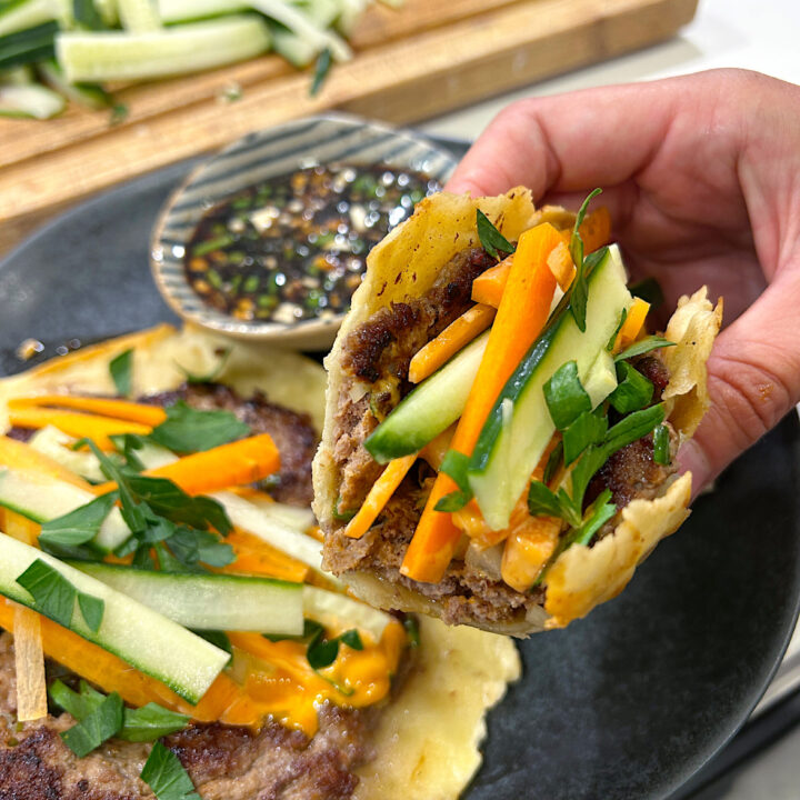 an asian inspired taco with ground meat, cucumbers, carrots and a soy dipping sauce