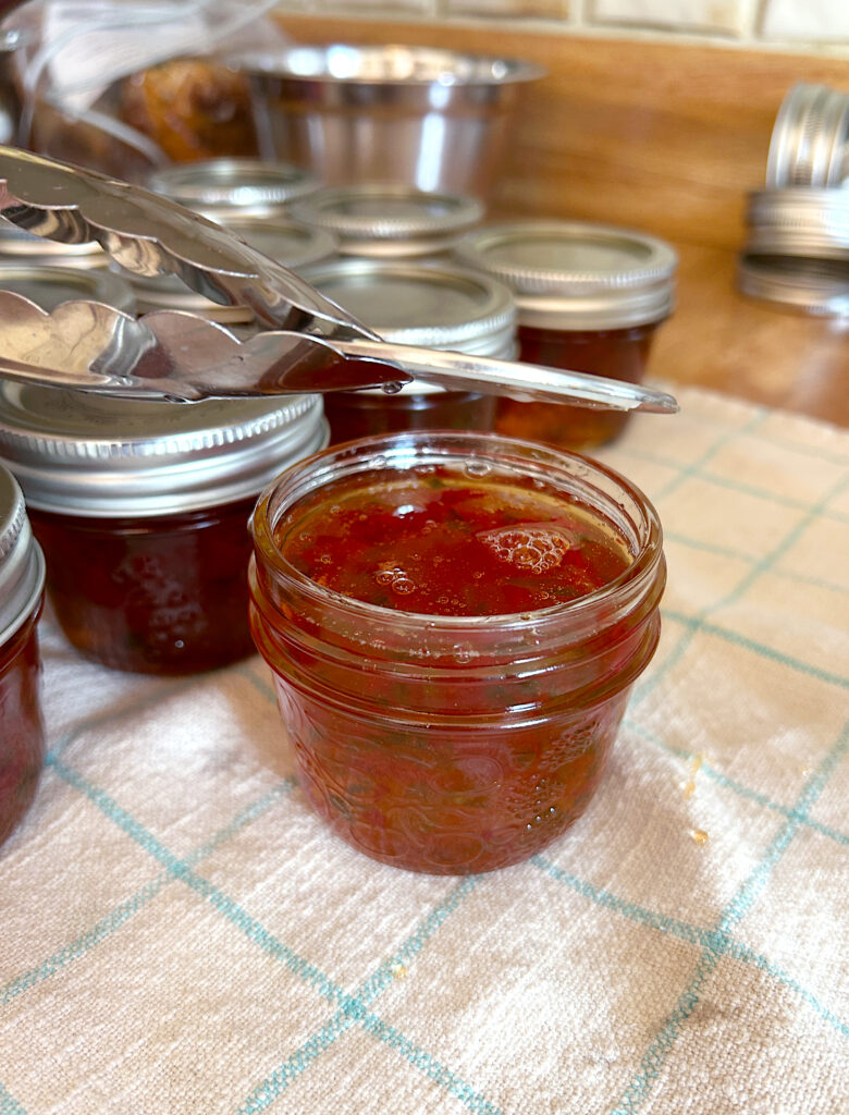 a lid being placed on a jar of pepper jelly 