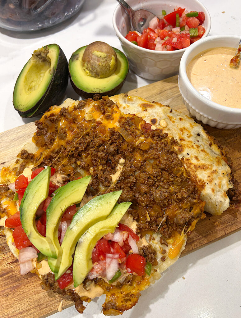 a taco filled with ground venison, cheese, avocado and pice de Gallo