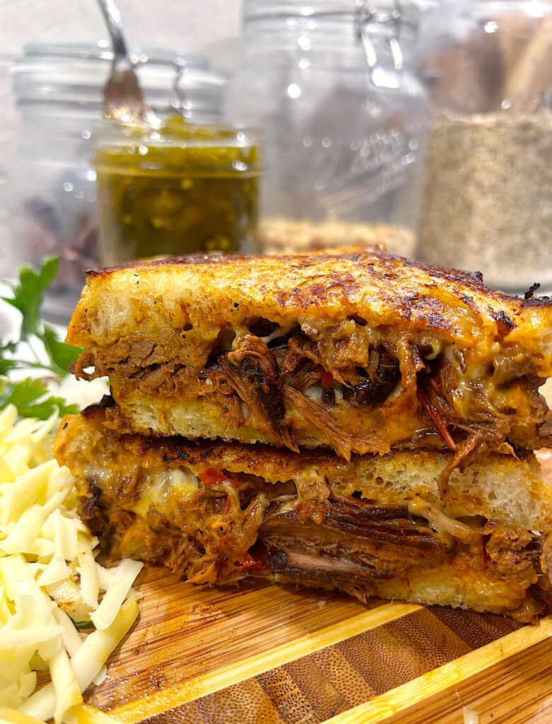 a sandwich with shredded meat and cheese, toasted and cut I half