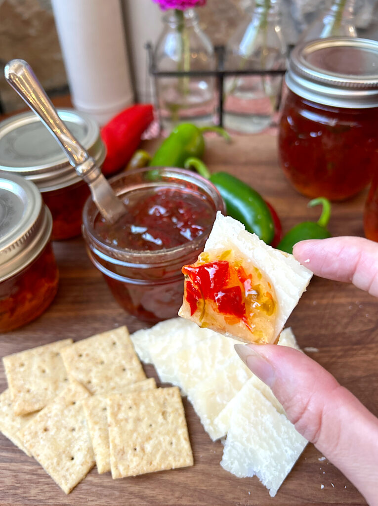 a cracker with cheese and pepper jelly on top
