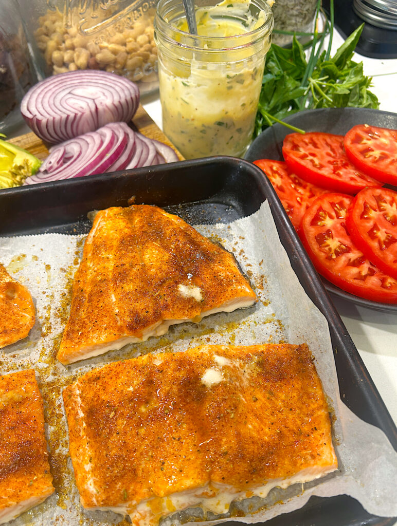 a tray of baked salmon with a slide of sliced tomatoes and aioli 