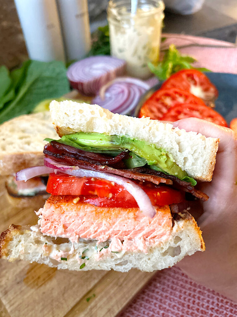 a homemade sandwich with salmon, bacon and tomato