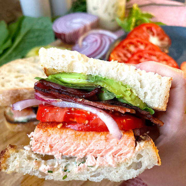 a homemade sandwich with salmon, bacon and tomato