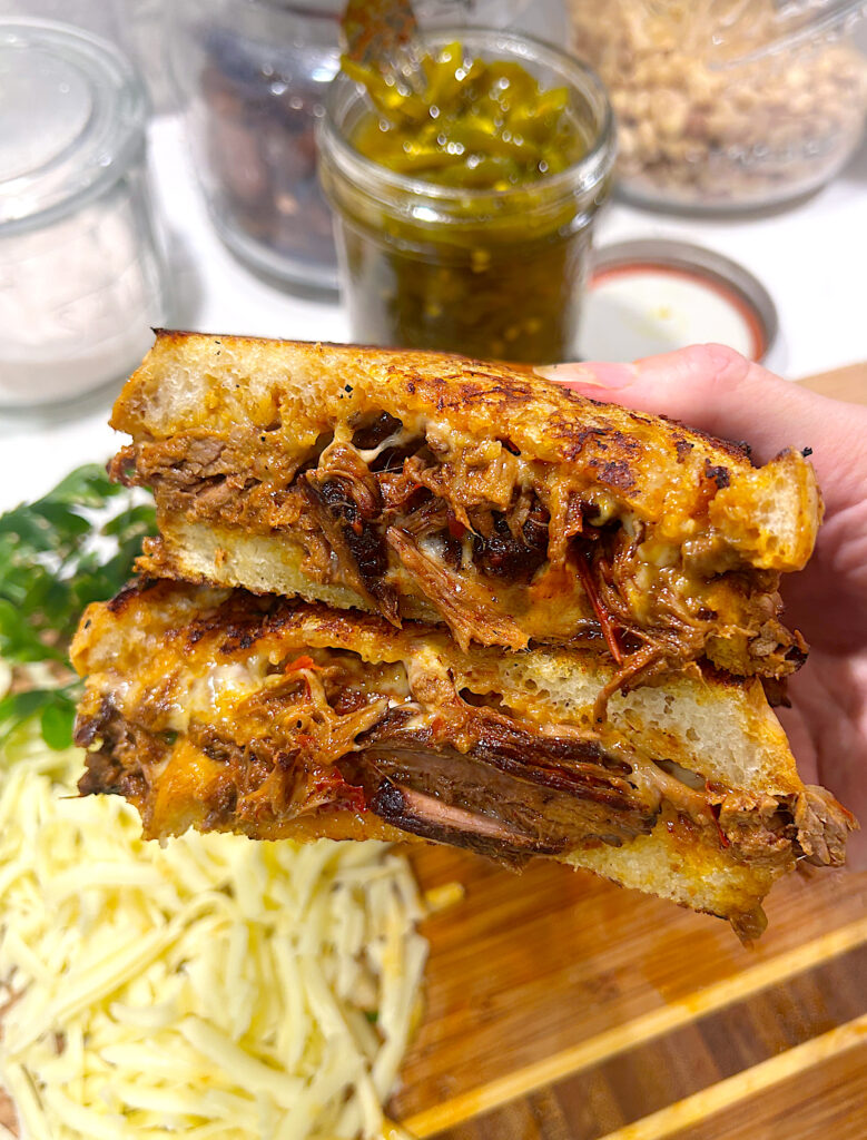 a grilled cheese cut in half full of shredded birria meat
