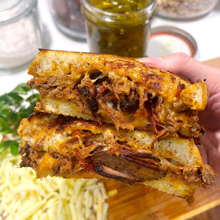 a grilled cheese cut in half full of shredded birria meat