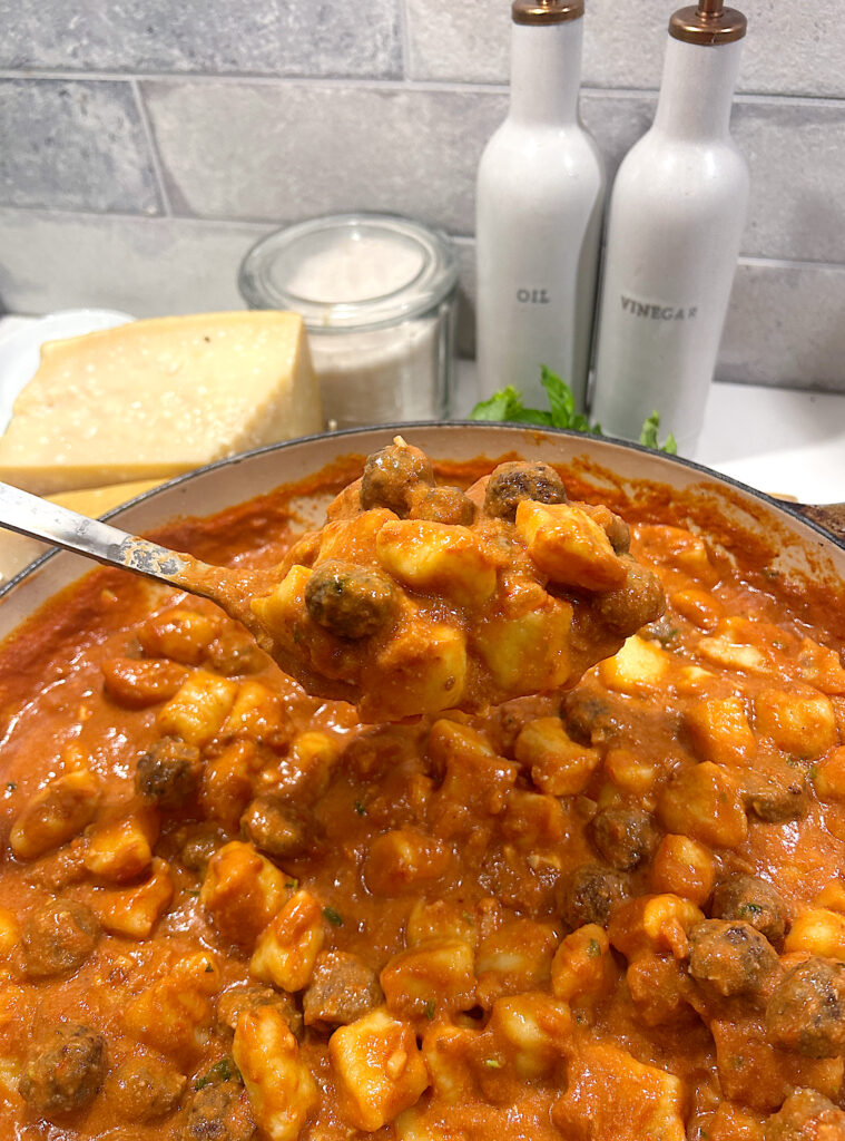 a spoonful of gnocchi and meatballs in a creamy tomato sauce