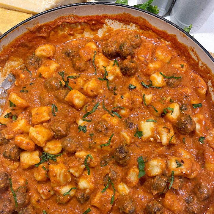 a skillet of creamy tomato gnocchi and mini meatballs