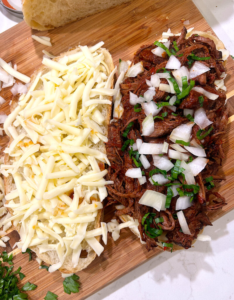 bread topped with shredded cheese and birria