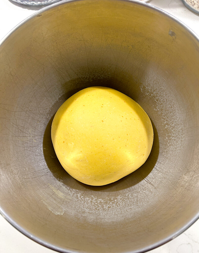a stainless bowl of pumpkin bread dough