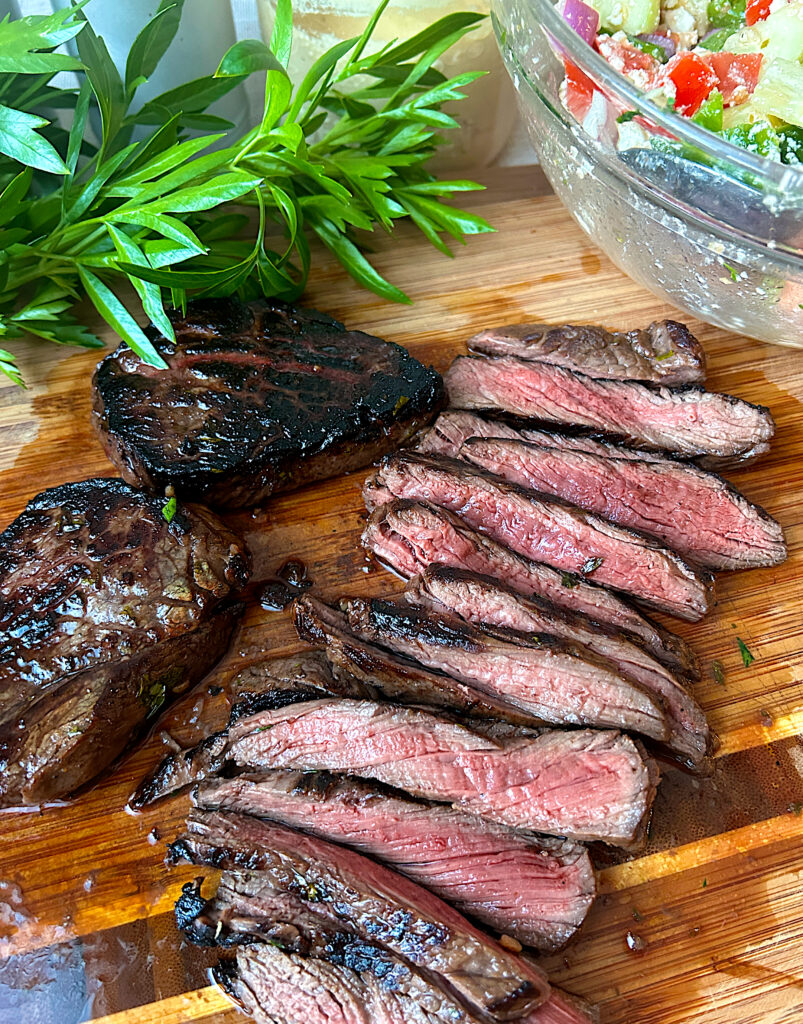 medium rare sliced steak on a wood board