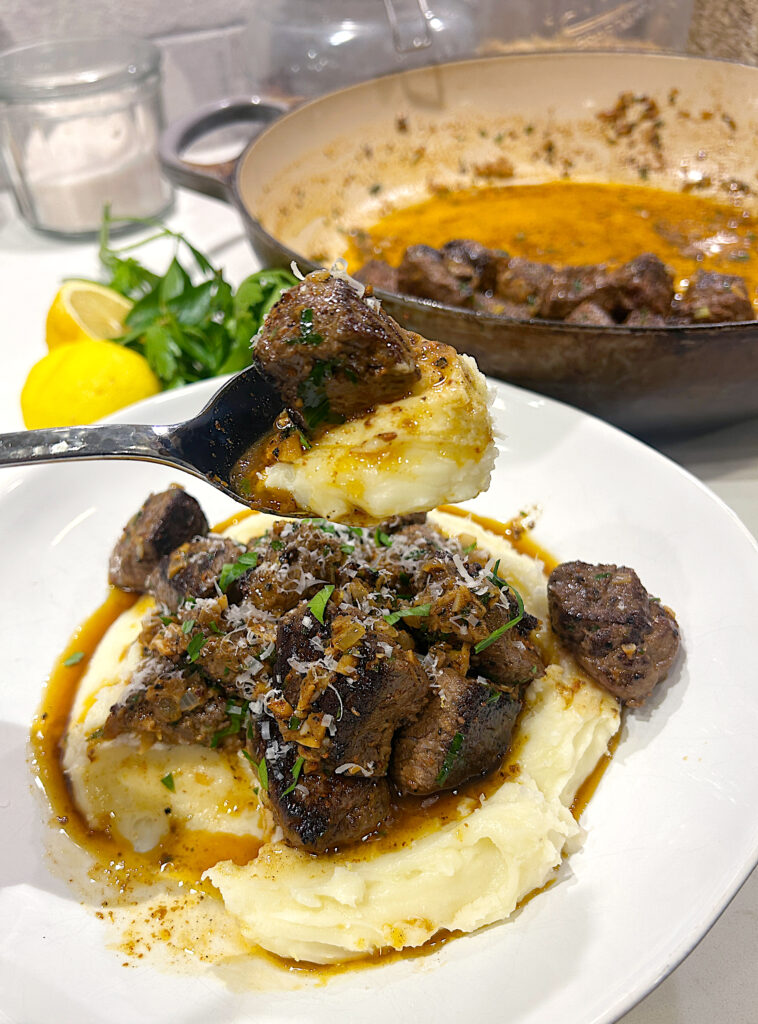 a spoonful of mashed potatoes with a bite of seared steak