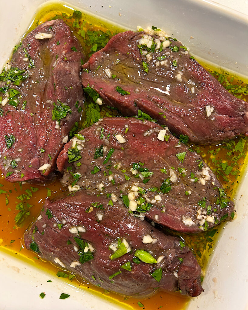 raw steaks in a garlic and herb marinade