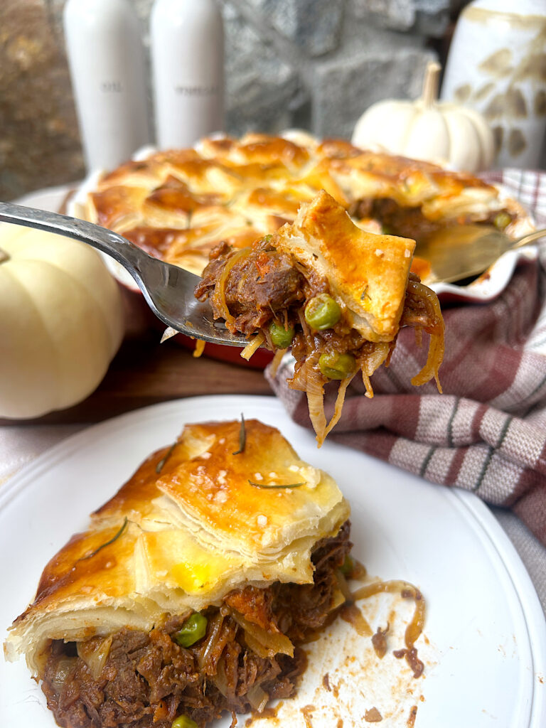 a slice of meat pie with venison, peas and carrots topped with flaky pie crust